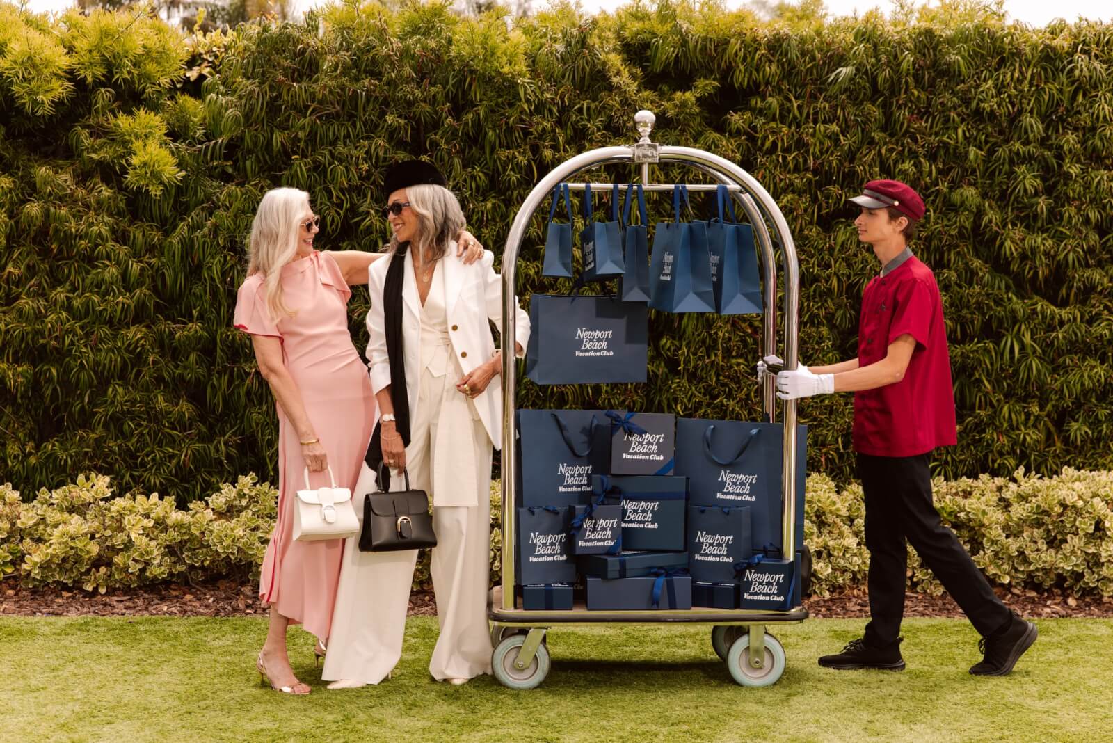 2 women and a bellhop with a cart full of bags