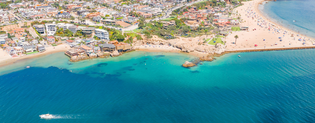 An aerial view of the stunning coastline of Corona del Mar, with azure waters meeting golden sands, capturing the serene beauty of this coastal paradise.
