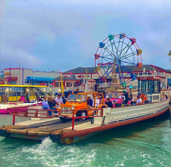 cars on a pier with a ferris wheel in the background