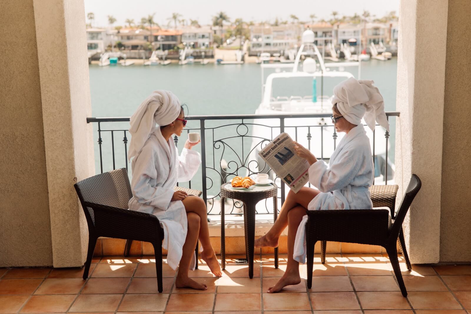 2 girls sitting on a balcony with towels on their head