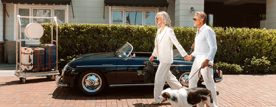 2 people walking in front of car with dog