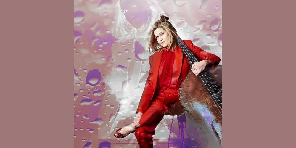 Woman in red suit holding a bass instrument.
